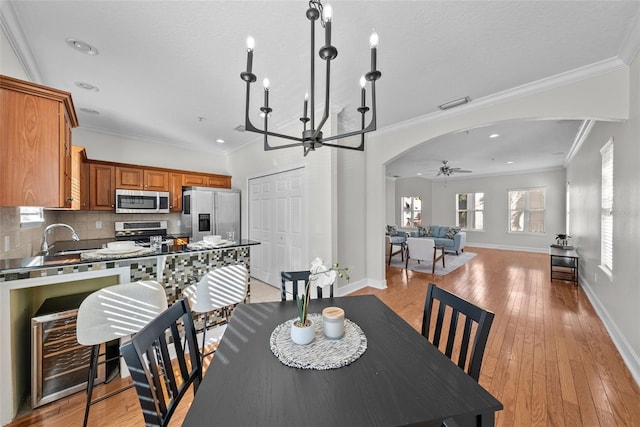 dining space with ceiling fan, ornamental molding, sink, and light wood-type flooring