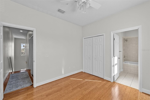 unfurnished bedroom with a closet, connected bathroom, ceiling fan, and light hardwood / wood-style flooring