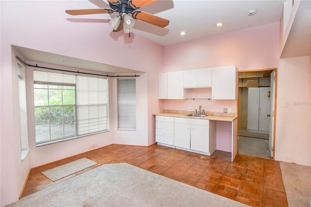 kitchen featuring lofted ceiling, light parquet floors, white cabinets, sink, and ceiling fan