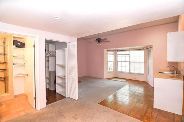 interior space with ceiling fan, light colored carpet, and sink