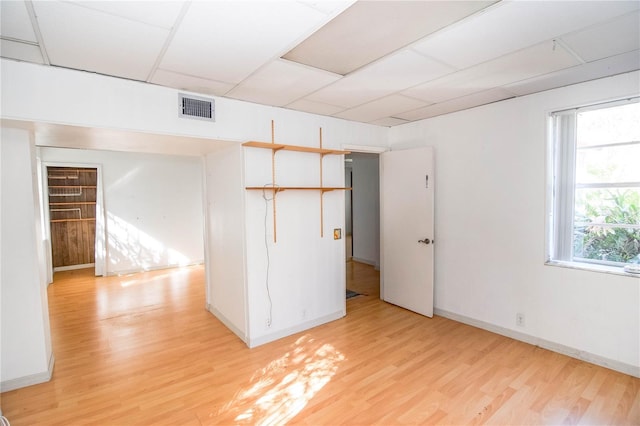 spare room featuring light wood-type flooring and a paneled ceiling