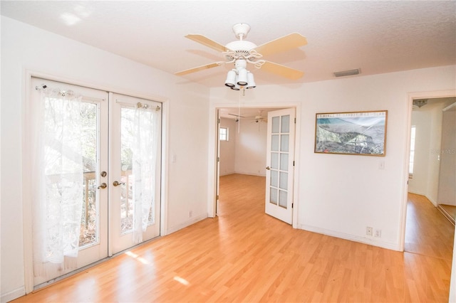 interior space featuring ceiling fan, french doors, a textured ceiling, and light hardwood / wood-style flooring