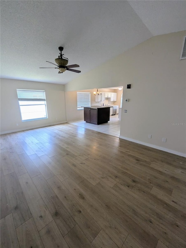 unfurnished living room with ceiling fan, hardwood / wood-style floors, and lofted ceiling