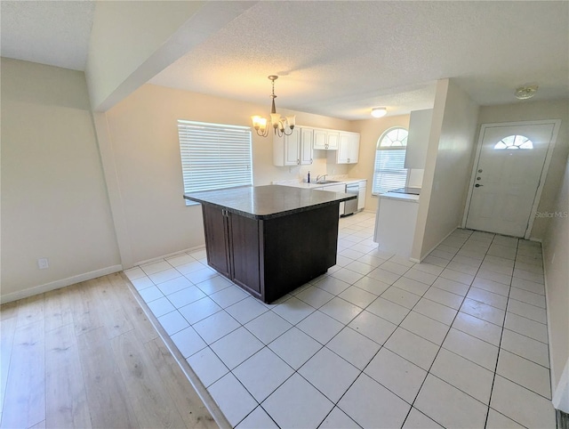 kitchen featuring white cabinetry, sink, dishwasher, a notable chandelier, and decorative light fixtures