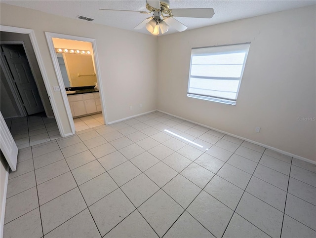 unfurnished bedroom featuring light tile patterned floors, ensuite bathroom, and ceiling fan