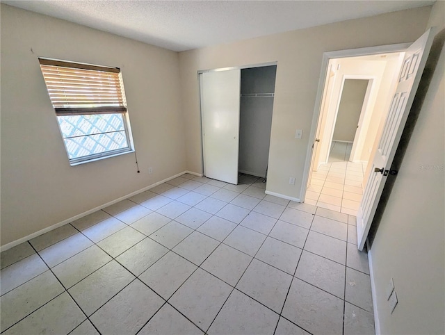 unfurnished bedroom featuring a closet, light tile patterned flooring, and a textured ceiling