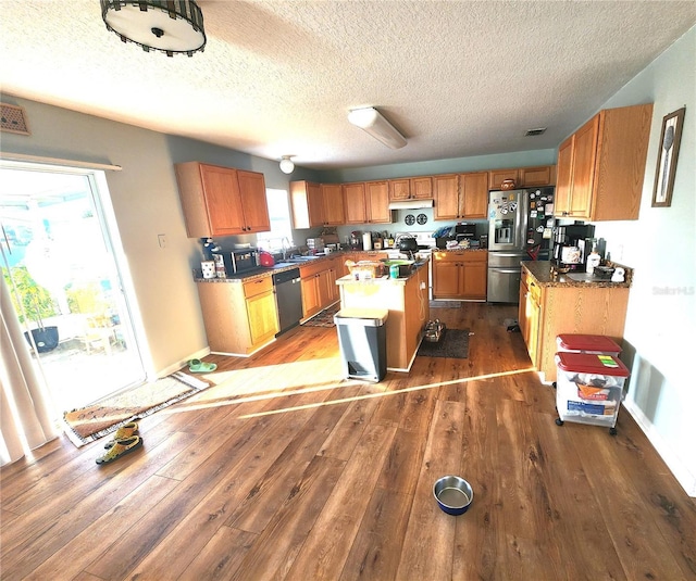 kitchen with wood-type flooring, a center island, stainless steel appliances, and a textured ceiling