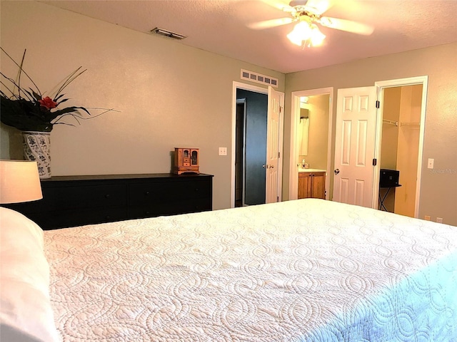 bedroom featuring connected bathroom, a spacious closet, ceiling fan, sink, and a closet