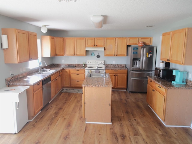 kitchen featuring stainless steel appliances, a kitchen island with sink, hardwood / wood-style flooring, and sink