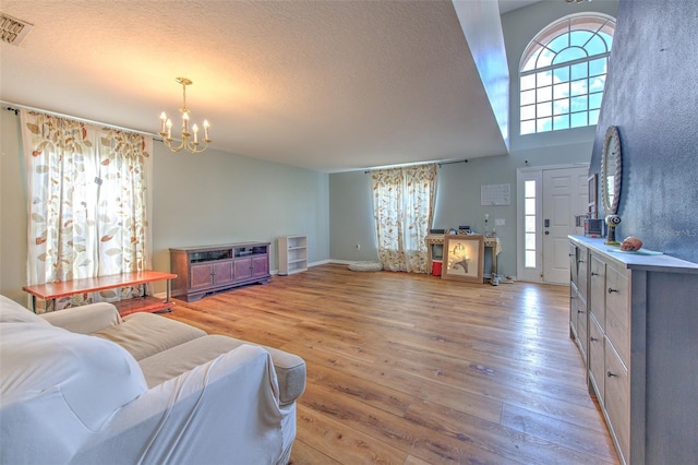 living room with an inviting chandelier, light hardwood / wood-style flooring, and a textured ceiling