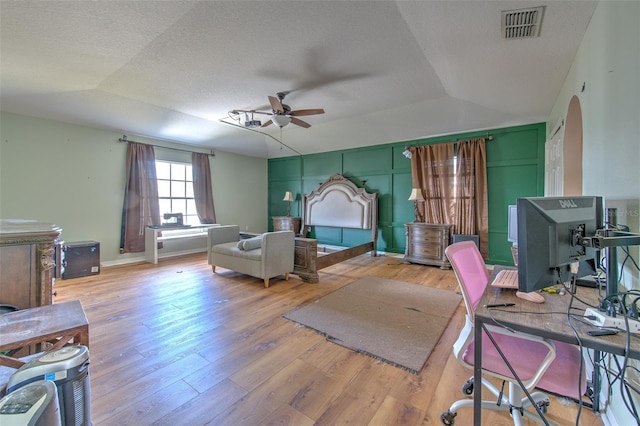 bedroom with light hardwood / wood-style flooring, a textured ceiling, and vaulted ceiling