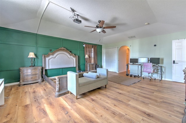 bedroom with vaulted ceiling, light hardwood / wood-style floors, and a textured ceiling