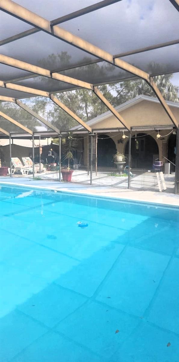 view of swimming pool featuring glass enclosure