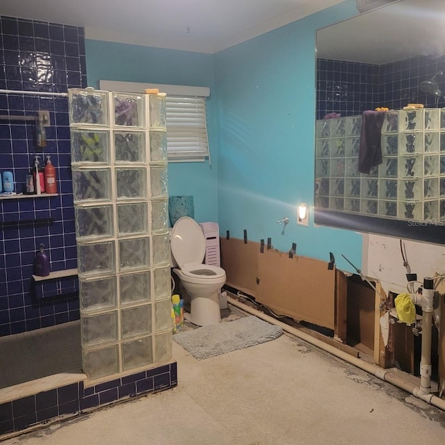 bathroom with toilet, concrete flooring, and a tile shower