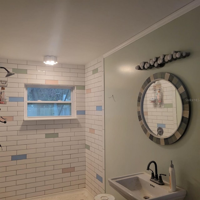 bathroom featuring ornamental molding, a tile shower, and sink