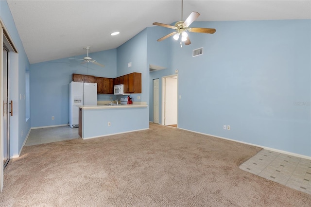 kitchen with light colored carpet, white appliances, kitchen peninsula, and high vaulted ceiling