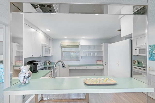 kitchen with white cabinetry, sink, kitchen peninsula, hardwood / wood-style floors, and white appliances