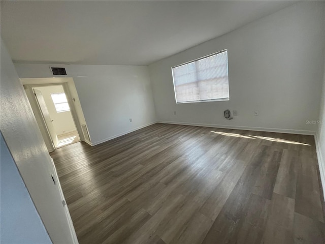 spare room with a wealth of natural light and dark hardwood / wood-style flooring