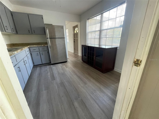 kitchen with stainless steel refrigerator, hardwood / wood-style floors, gray cabinets, and sink