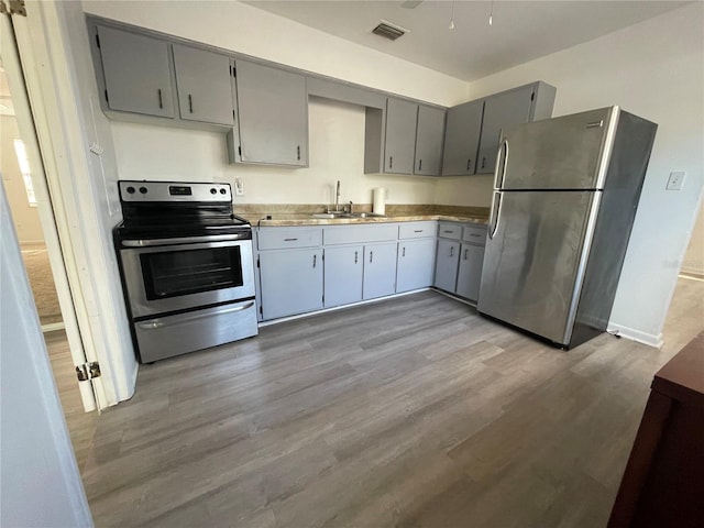 kitchen featuring stainless steel appliances, gray cabinets, light hardwood / wood-style floors, and sink