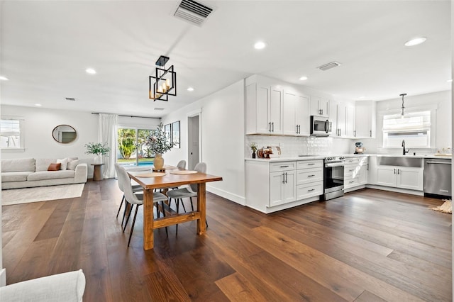 kitchen featuring appliances with stainless steel finishes, dark hardwood / wood-style flooring, white cabinetry, and pendant lighting