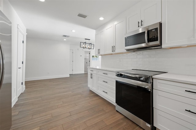 kitchen with white cabinetry, light hardwood / wood-style flooring, pendant lighting, and appliances with stainless steel finishes