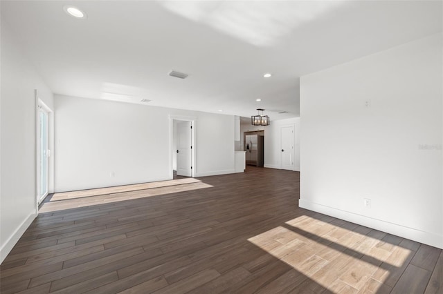 unfurnished living room with dark wood-type flooring and a chandelier