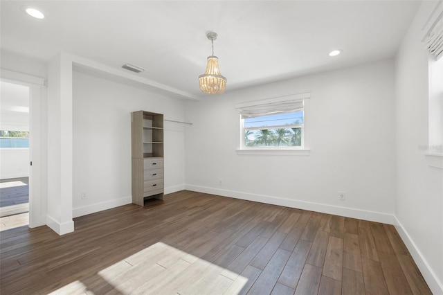 unfurnished bedroom featuring dark hardwood / wood-style floors and a chandelier