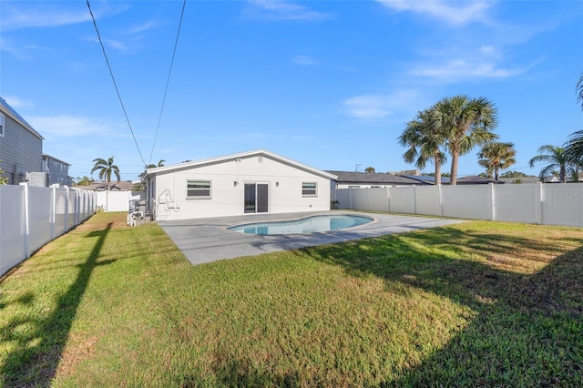 rear view of property with a lawn, a patio area, and a fenced in pool