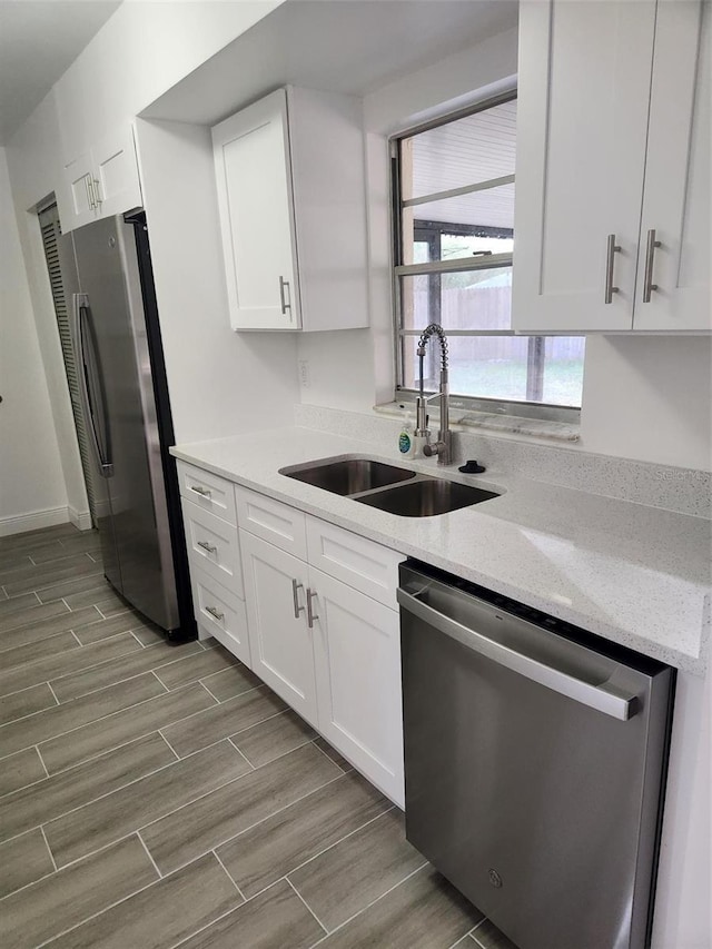 kitchen featuring light stone counters, sink, white cabinetry, and stainless steel appliances