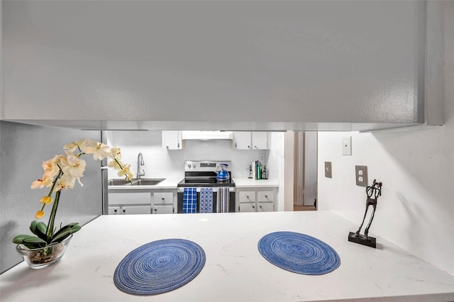 kitchen with electric range, white cabinetry, sink, and exhaust hood