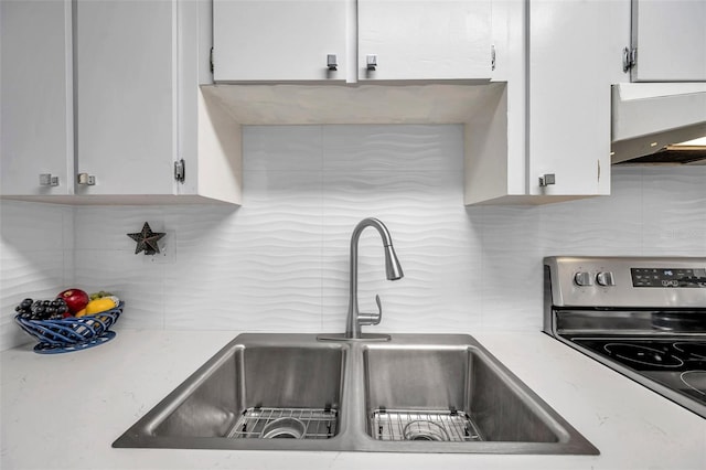 kitchen with tasteful backsplash, exhaust hood, sink, white cabinets, and stainless steel electric range