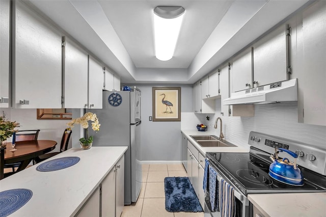 kitchen with sink, a tray ceiling, decorative backsplash, light tile patterned flooring, and appliances with stainless steel finishes