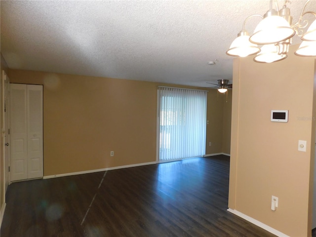 empty room featuring a textured ceiling, ceiling fan with notable chandelier, and dark hardwood / wood-style floors