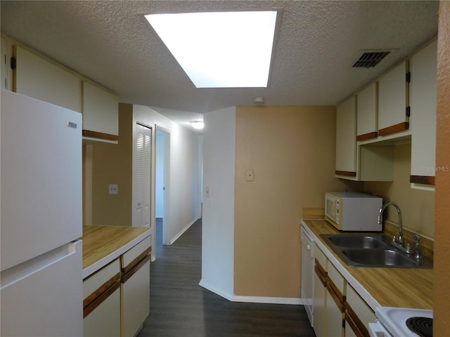 kitchen with sink, dark wood-type flooring, a textured ceiling, white appliances, and white cabinets