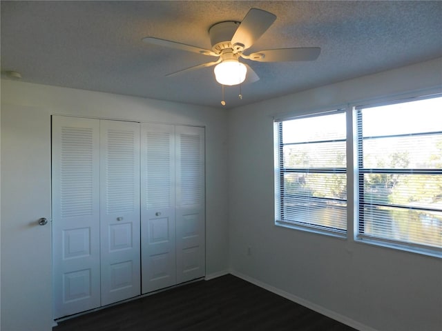 unfurnished bedroom featuring a textured ceiling, ceiling fan, a closet, and dark hardwood / wood-style floors