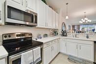 kitchen featuring a chandelier, white cabinets, stainless steel appliances, and decorative light fixtures