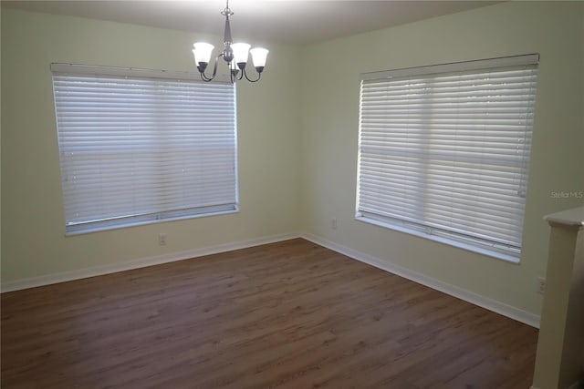 unfurnished room featuring an inviting chandelier and dark wood-type flooring