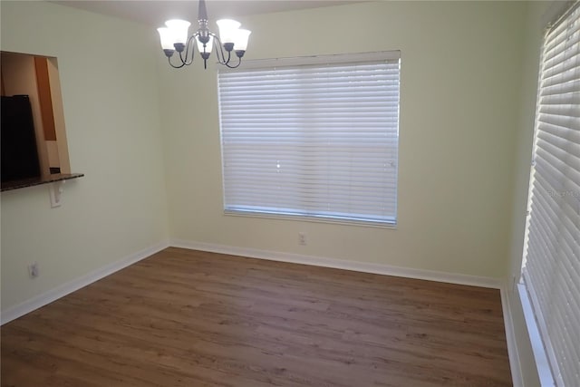 unfurnished dining area featuring a notable chandelier and dark hardwood / wood-style flooring