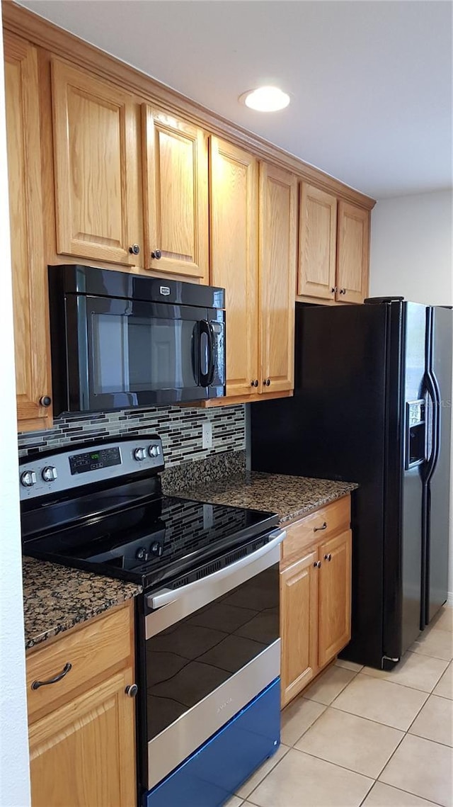 kitchen featuring light tile patterned floors, backsplash, dark stone countertops, and black appliances