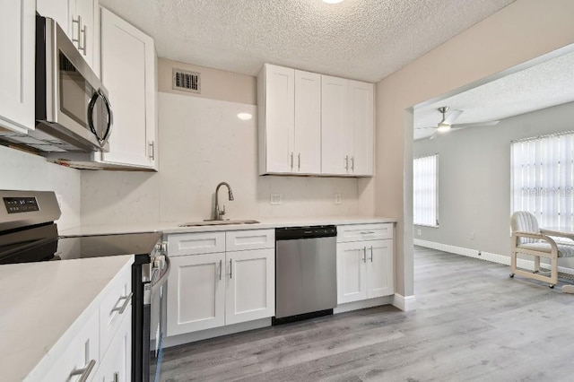 kitchen with white cabinetry, sink, stainless steel appliances, and a textured ceiling