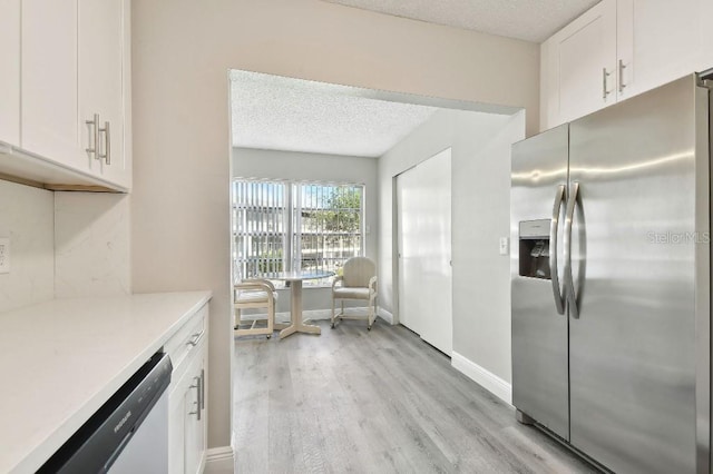 kitchen with light hardwood / wood-style flooring, white cabinets, a textured ceiling, and appliances with stainless steel finishes