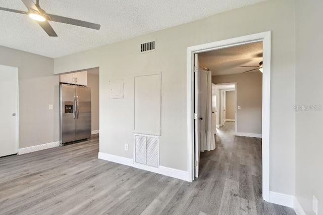 empty room featuring a textured ceiling, light hardwood / wood-style flooring, and ceiling fan