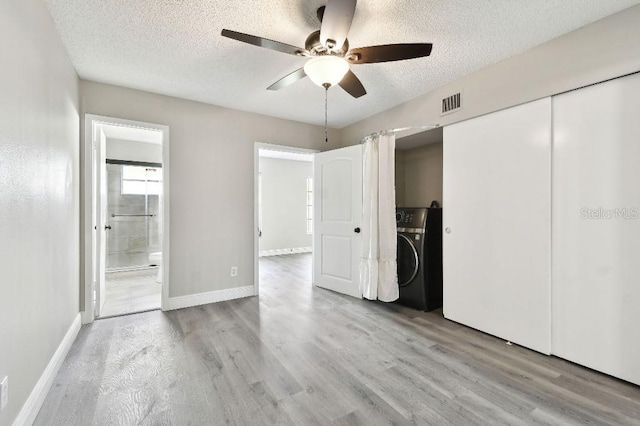 unfurnished bedroom with ensuite bath, a textured ceiling, ceiling fan, washer / clothes dryer, and a closet