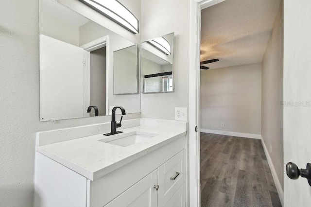 bathroom with ceiling fan, vanity, wood-type flooring, and a textured ceiling