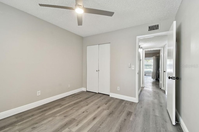 unfurnished bedroom featuring a textured ceiling, a closet, ceiling fan, and light hardwood / wood-style floors