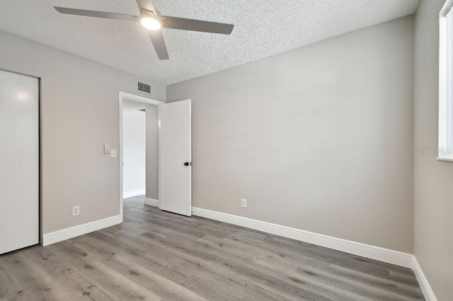 unfurnished bedroom featuring ceiling fan, light hardwood / wood-style floors, and a textured ceiling