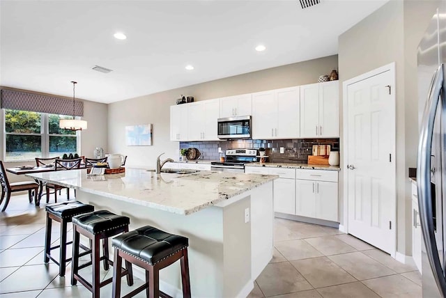 kitchen with pendant lighting, sink, an island with sink, appliances with stainless steel finishes, and white cabinetry