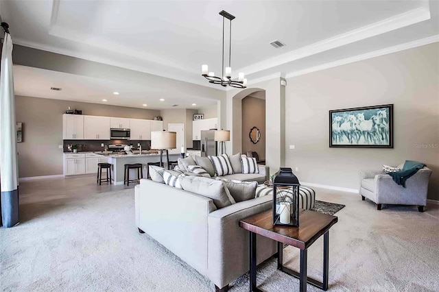 living room featuring a tray ceiling, crown molding, and an inviting chandelier