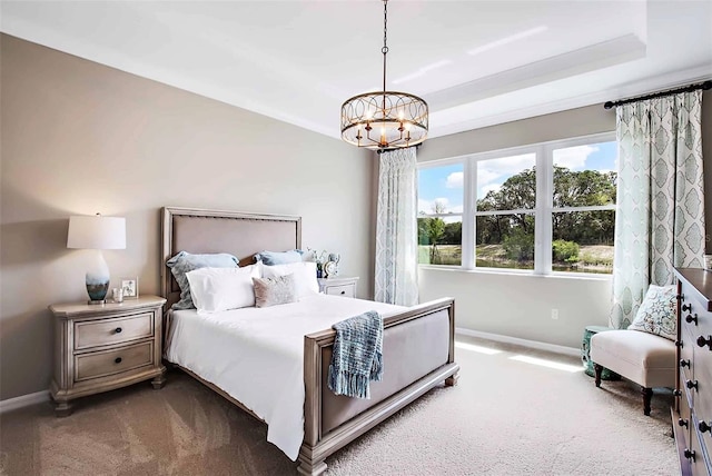 bedroom with carpet flooring, a tray ceiling, and an inviting chandelier